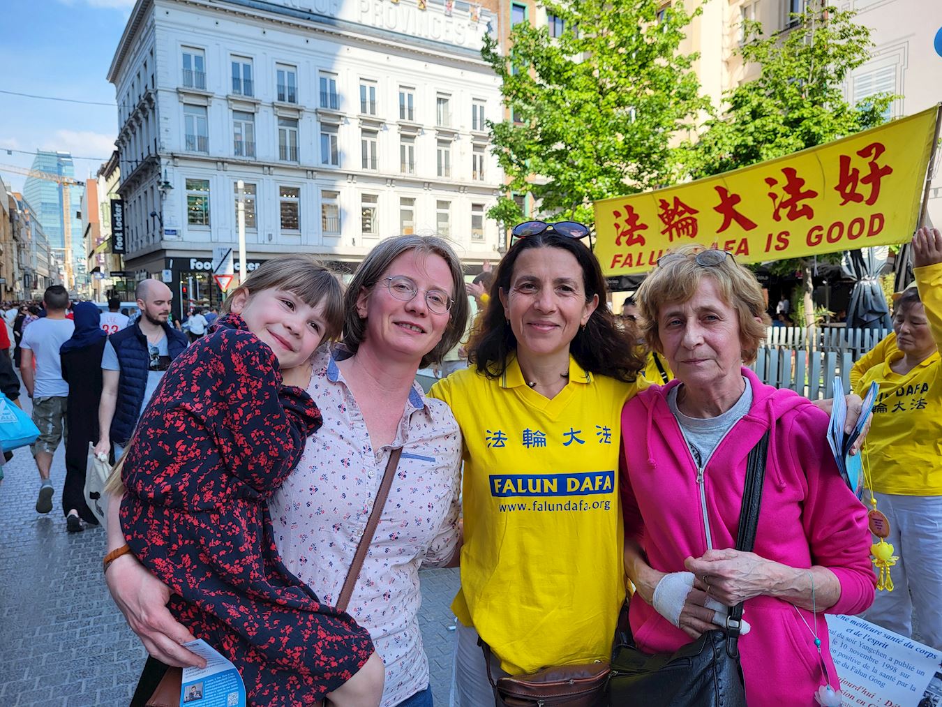 '图9:玛瑞娜怀抱着女儿和母亲与学员合影。她认为遵循真善忍普世法则以达到平静中找到自我是个好主意。'