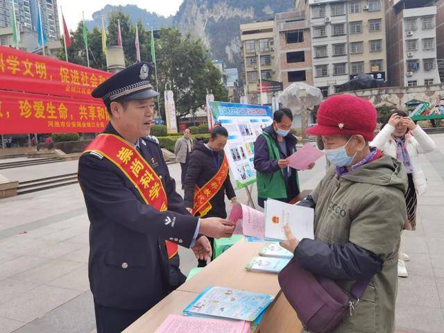 韦晓锋(左一)在河池市政法委、市公安局、金城江分局组织的“崇尚科学 反对邪教”现场发污蔑资料毒害众生。