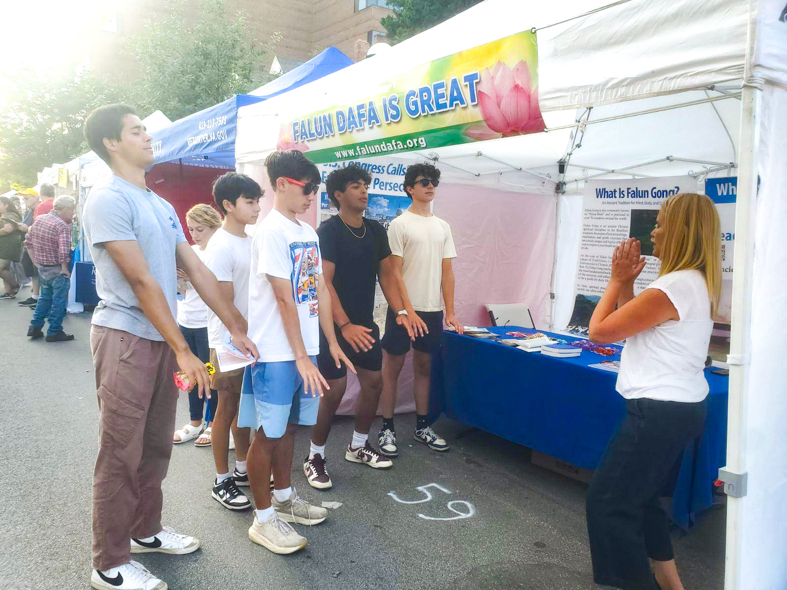 图7:一群青少年在展位前学炼法轮功的第一套功法