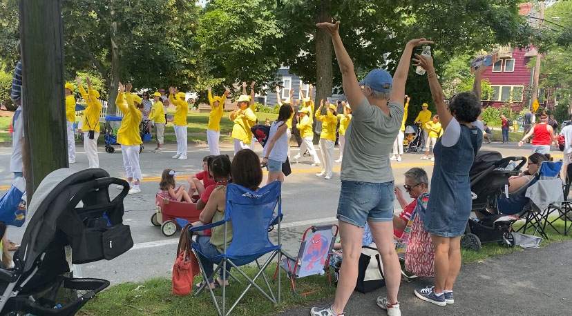 图2~3:法轮功学员在游行途中展示法轮功缓、慢、圆的功法,受到人们喝彩赞赏,有的观众正认真地学起了功法动作。