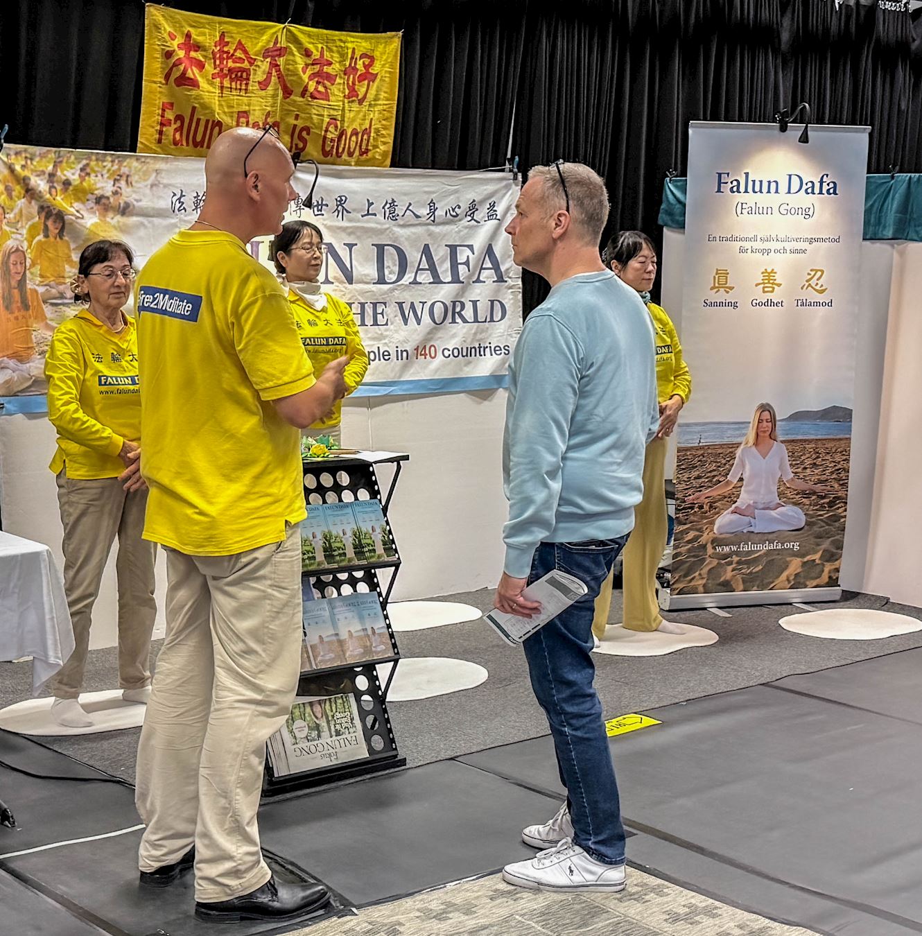 '图1~3:法轮功学员在展台前向参观者介绍以修炼真、善、忍为原则的法轮功,并演示功法。'