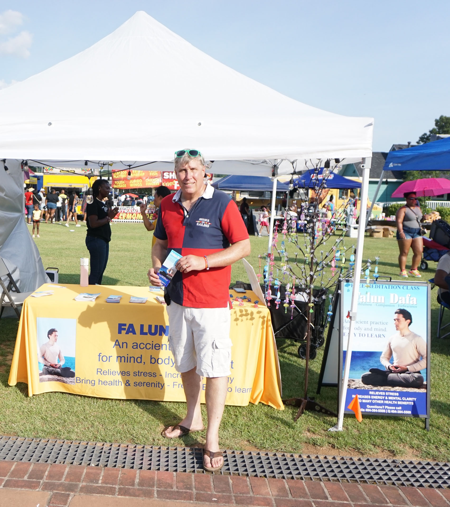 图3:莫洛城市市长约翰·兰普尔在法轮功功法介绍和免费教功摊位上