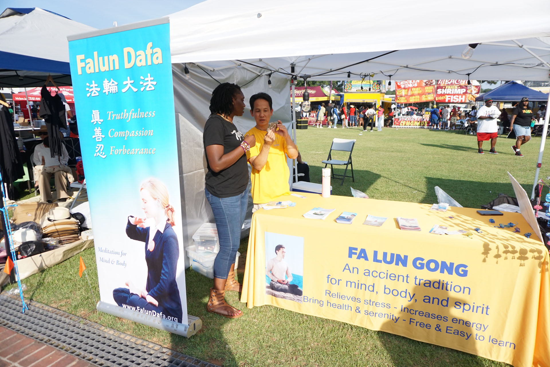 图5:卡莎娜·埃尔姆斯女士(左一)主动来到介绍法轮功的摊位学功。