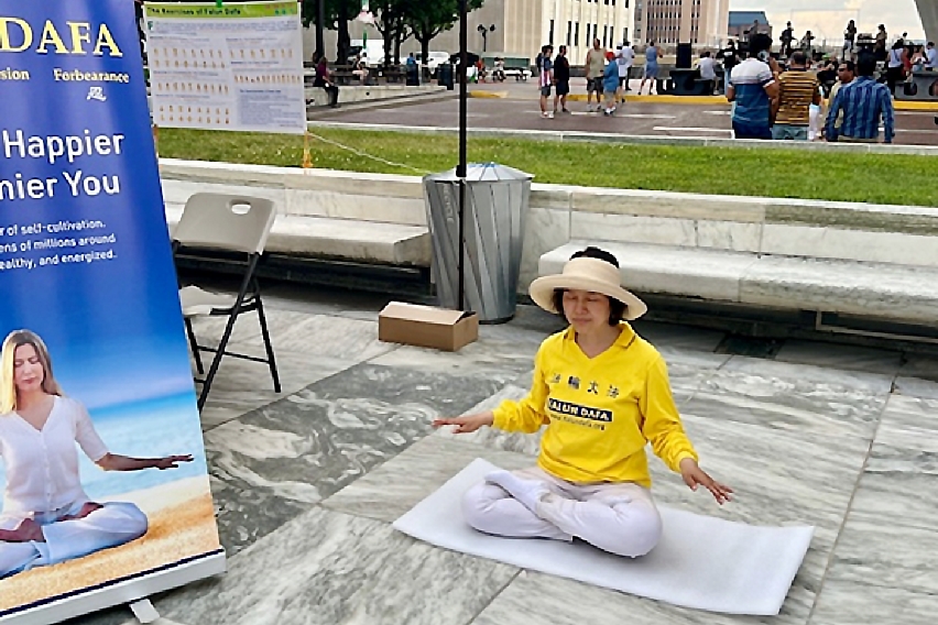 图3~4:法轮功学员在纽约州帝国大厦广场的展台旁向市民及游客演示法轮功第五套功法、弘法讲真相。