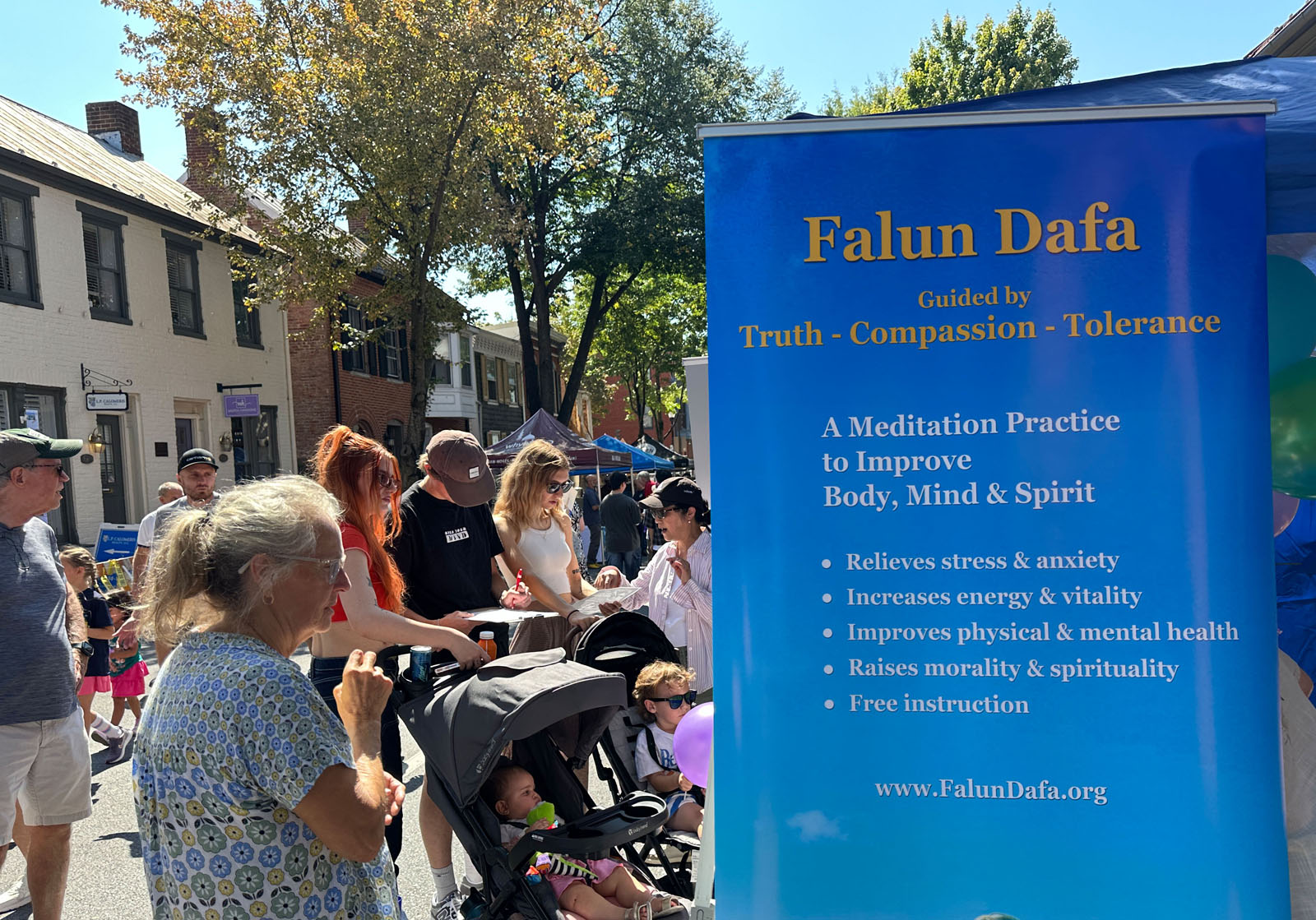 图1~2: 二零二五年九月十三日,美国马里兰州部份法轮功学员在弗雷德里克市的街头节庆上摆设展位,向民众介绍法轮大法,并讲述法轮功遭受中共迫害的真相。