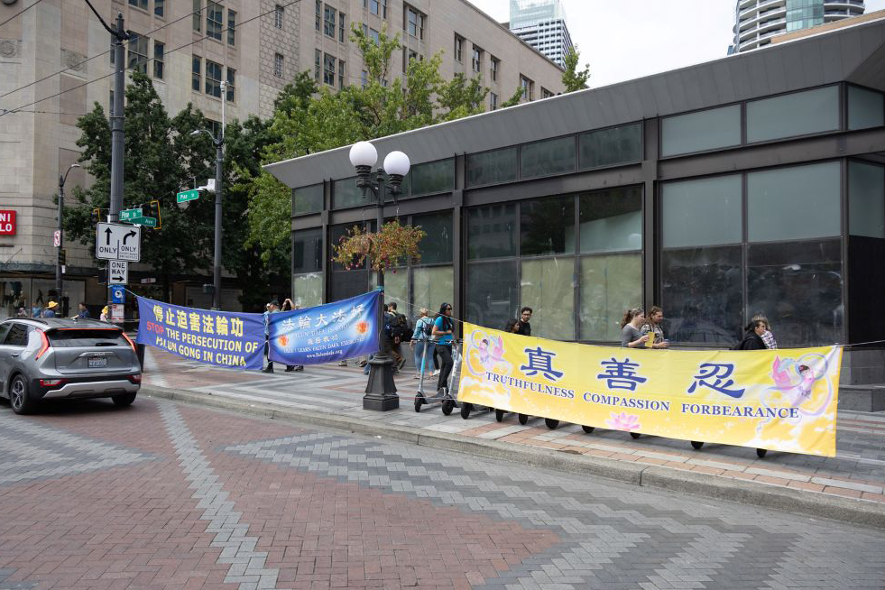 图1~2:西雅图部份法轮功学员多年来坚持不懈地在西雅图热闹的都市绿洲旁边的十字路口,拉横幅、讲真相、征签反迫害。引起不少是频驻足关注。